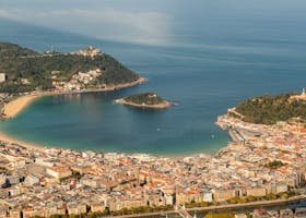 A stunning aerial view of La Concha Bay, San Sebastián, with lush hills and cityscape.